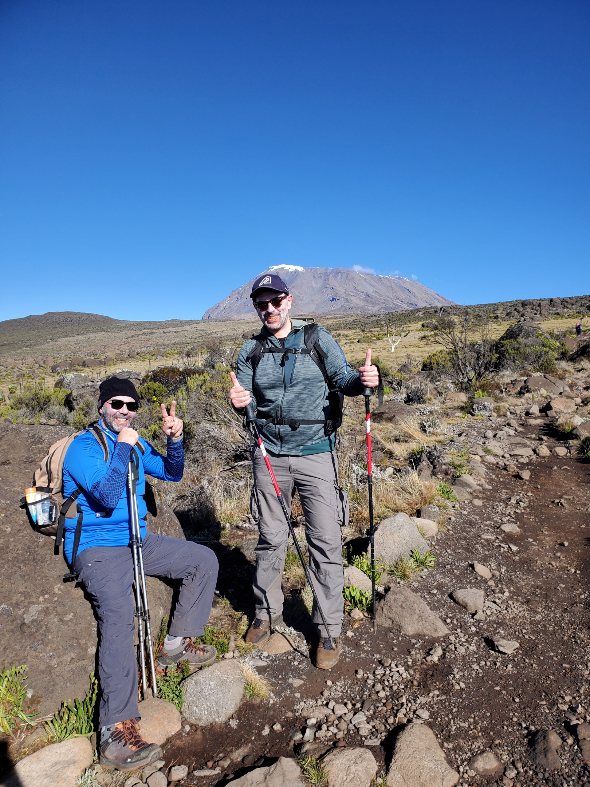 Hikers walking across Shira Plateau with Kilimanjaro’s summit in the background.